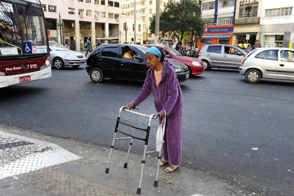 Maria da Penha, perto dos oitenta, conta com a ajuda ocasional de pedestres para atravessar
